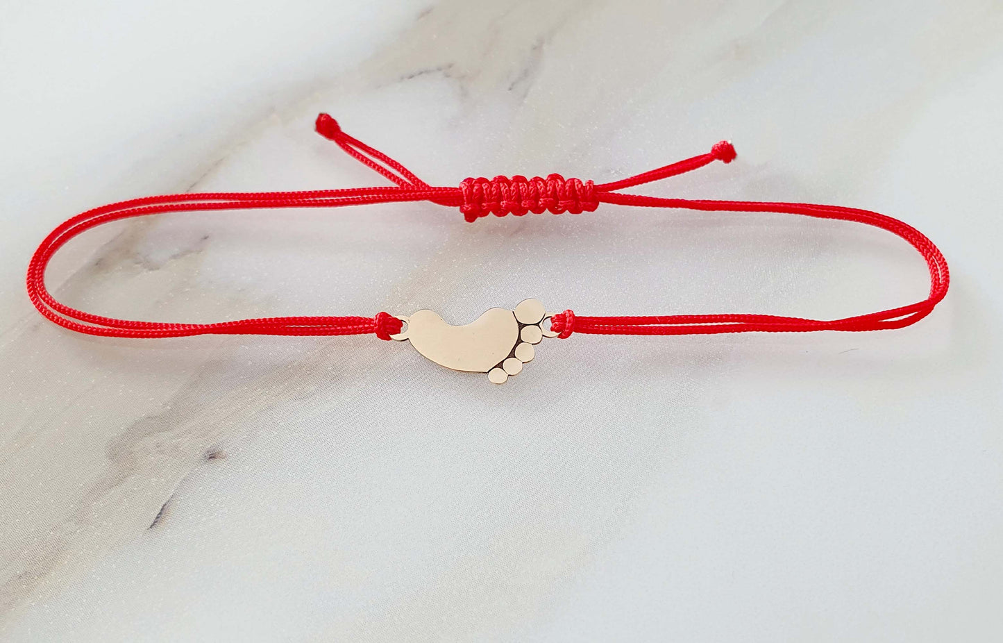 Raudono siūlo apyrankė su auksine pėdute