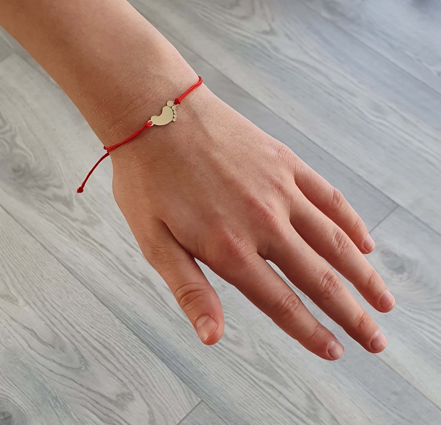 Raudono siūlo apyrankė su auksine pėdute